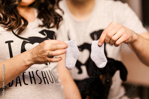 Pregnant woman and her husband are holding small socks for their future baby
