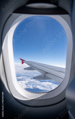 View from a window of an airplane showing plane wing and sky as background.Selective focus.
