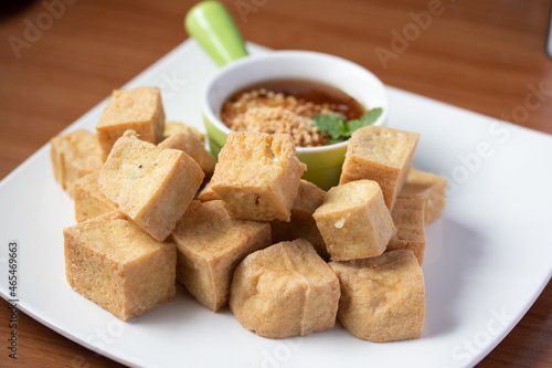 Fried tofu with Thai sweet dipping sauce in a white plate on the wooden floor