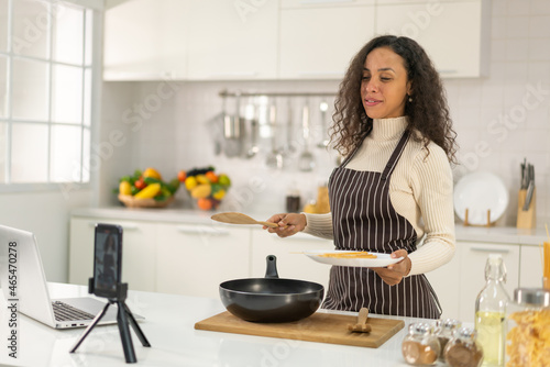 Latin woman shooting video and cooking at the kitchen