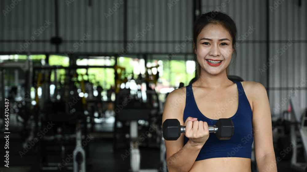 Young asian woman doing exercises with dumbbell in gym. Young asian woman doing exercises with dumbbell in gym.