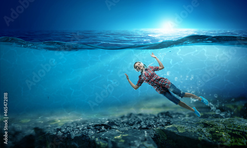 Woman wearing headphones underwater . Mixed media
