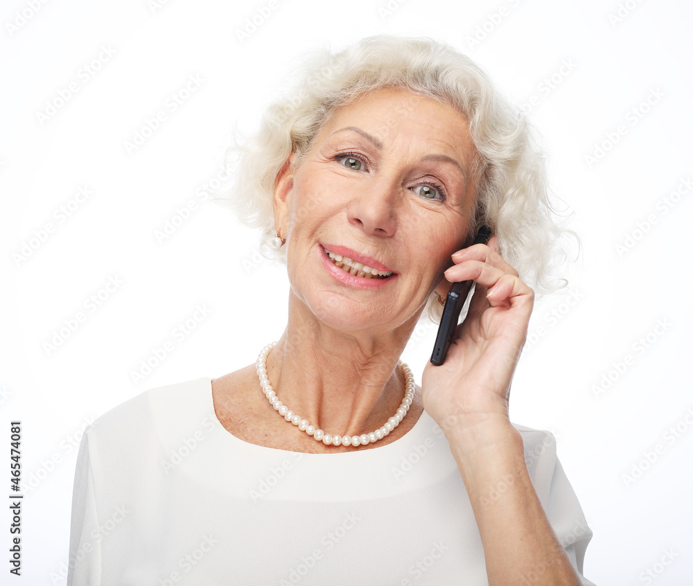 Portrait of attractive senior woman wearing white dress talking by mobile phone. Portrait of attractive senior woman wearing white dress talking by mobile phone.