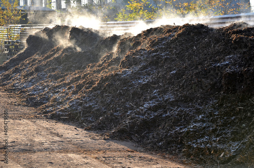 a pile of mulch bark from which it smokes in a frosty morning. there is a rapid release of heat when the compost decomposes. worn pieces of wood chips in a warehouse of gardeners photo