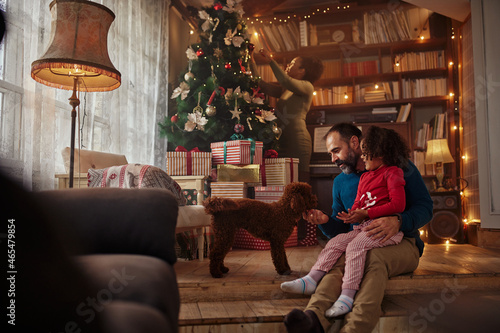 Father and daughter playing with dog during Christmastime
