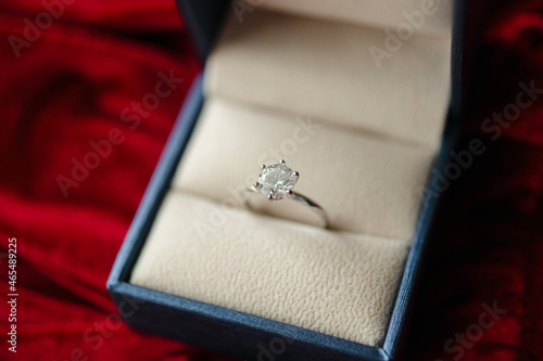 Diamond ring in jewelry gift box on red fabric background © Piman Khrutmuang