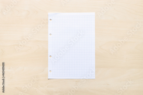 top view of blank sheet of squared paper on light brown wooden board photo