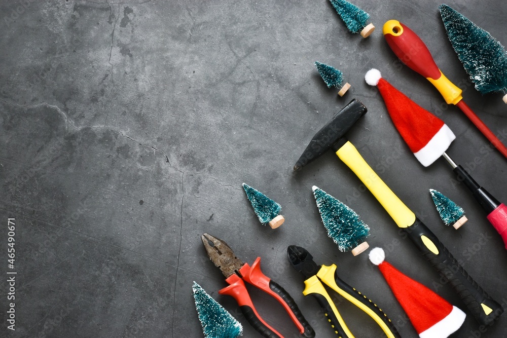 Christmas construction tools. Hammer, screwdrivers, brushes, pliers with decorative Christmas trees, santa claus hats on a gray background. Advertising concept. Card. Copy space, flat lay.