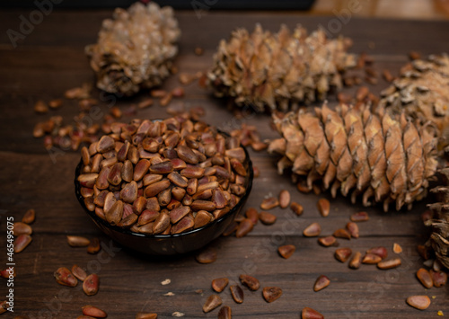 A pine cone and a walnut are lying on a wooden table
