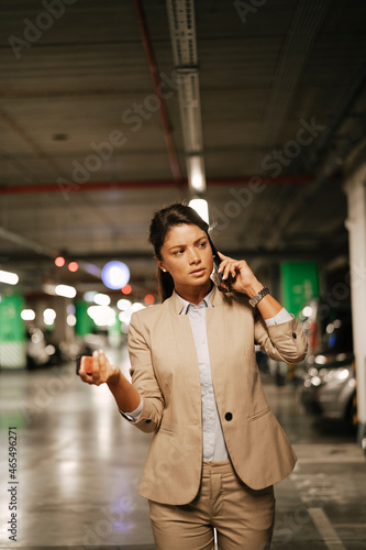 Tablou pe pânză Businesswoman in suit unlocking car on parking