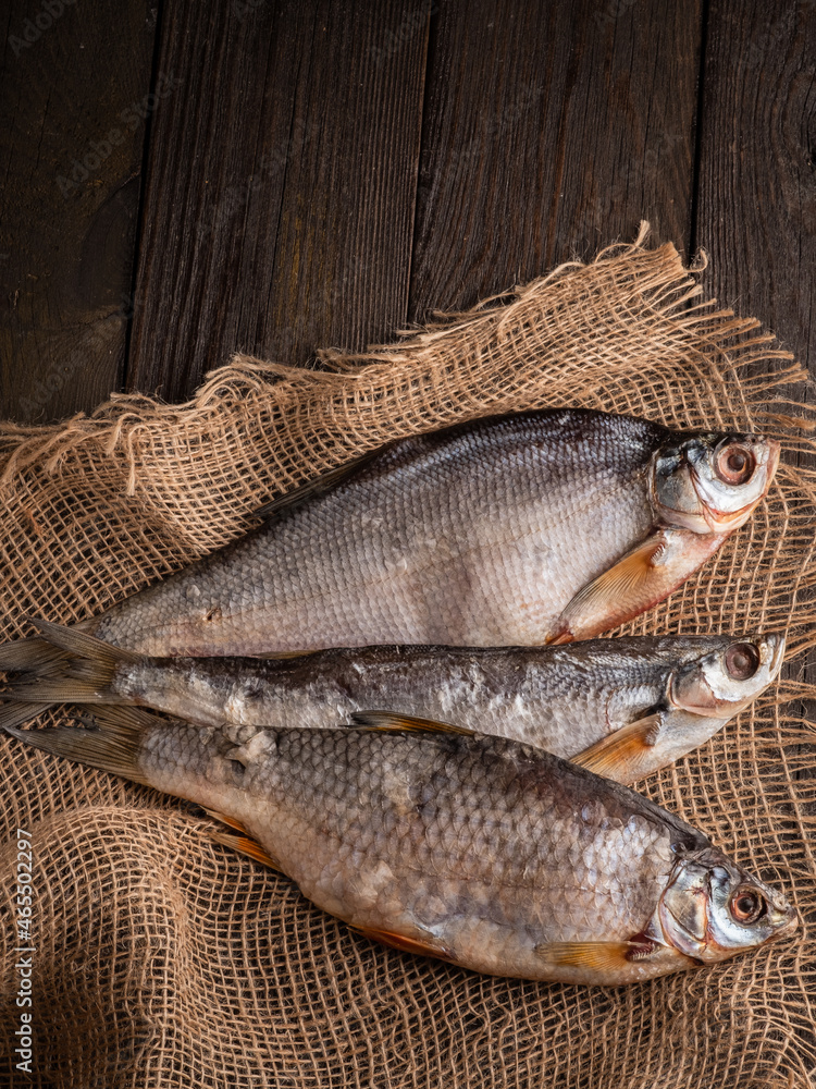 Obraz premium Dried fish stockfish on a brown wooden table. Top view with space for text