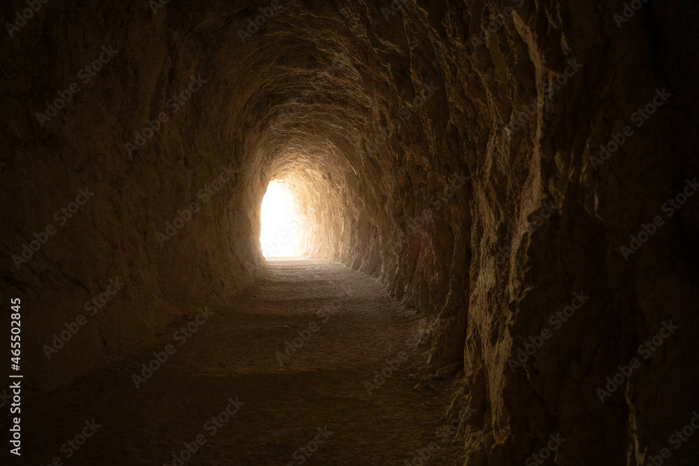 exit light in the end of a deep dark tunnel carved in stone
