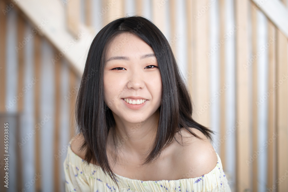 Portrait of a beautiful Asian young woman in a white trendy shirt at home in a light loft interior. Portrait of a beautiful Asian young woman in a white trendy shirt at home in a light loft interior.