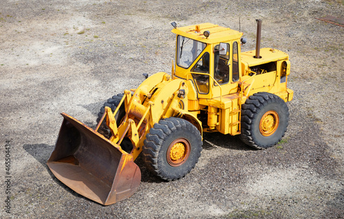 Wheel loader bulldozer with bucket standing in sandpit outdoors