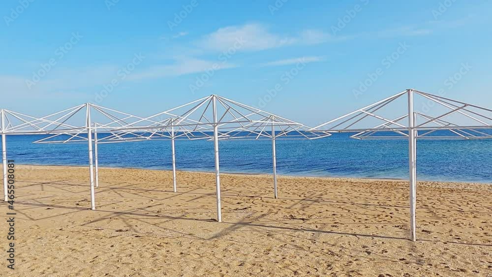 Frames of stationary beach umbrellas on sand and sea water surface at end of season. Frames of stationary beach umbrellas on sand and sea water surface at end of season.