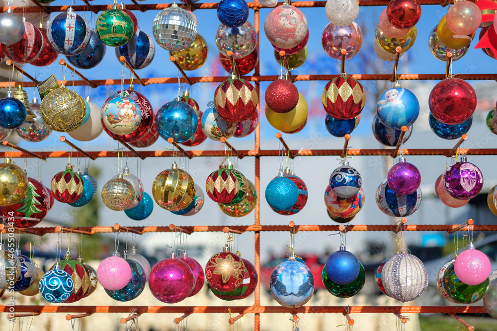Various colorful Christmas balls on the stand on a blurred background