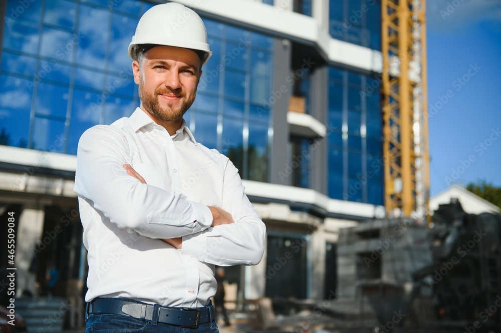 Portrait of man engineer at building site. Male construction manager wearing white helmet and yellow safety vest Portrait of man engineer at building site. Male construction manager wearing white helmet and yellow safety vest