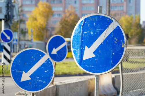 Photo of blue round road signs with white arrow on the street