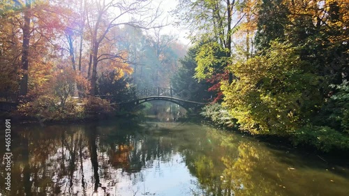 Scenic view of misty autumn landscape with beautiful old bridge the garden with red maple foliage.