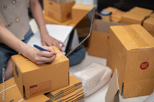 Female business owner working, packing the order for shipping to customer. Female entrepreneur packaging box for delivery. Online shopping e-commerce and logistic shipping freight transportation. © 22January