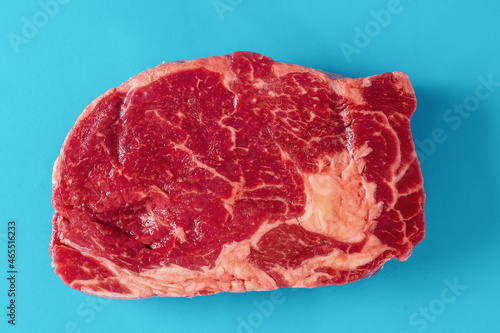 Fresh juicy rib eye steak on blue surface. Top quality fresh meat. Butcher craft product and meat industry. Rich red color and marbling. Premium cut.