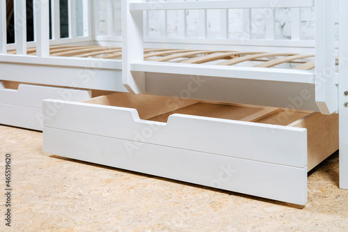The image of the child's bed, bottom view of the storage drawers. White beautiful furniture.