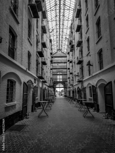 A narrow passage between the buildings. A landscape with many tables, windows and balconies