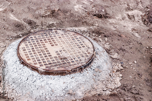 Installation of a heavy cast iron sewer manhole on a well. Sewerage system in construction.