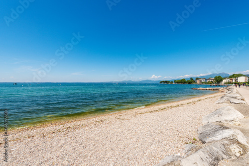 Beautiful empty beach and lakeshore of the Bardolino village  tourist resort on the coast of Lake Garda  Lago di Garda . Verona province  Veneto  Italy  Europe. On background the coast of Lombardy. 