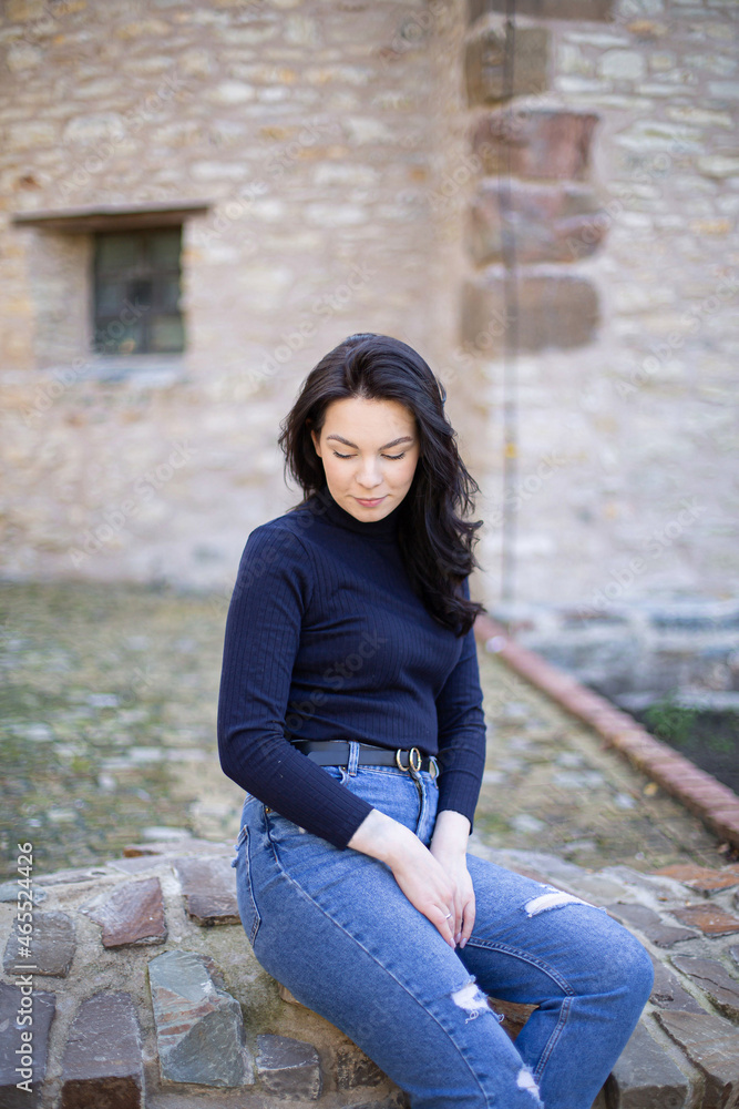Young white girl with dark hair in jeans outside with eyes down Young white girl with dark hair in jeans outside with eyes down