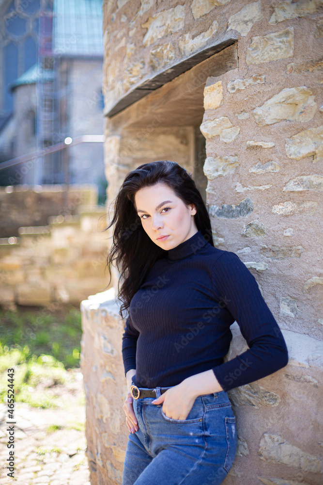 European young girl in jeans near the wall in navy blue sweater