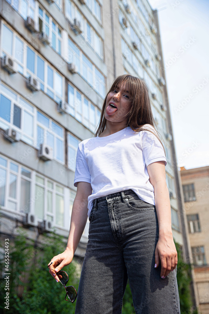 White european young girl with dark hair with building behind with tongue out