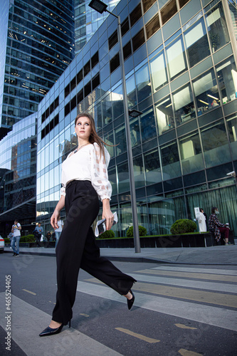 Walking young business woman on the street of a modern city