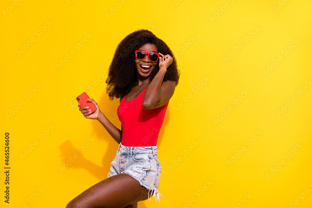 Photo of optimistic nice brunette lady hold telephone wear eyewear top shorts isolated on yellow color background Photo of optimistic nice brunette lady hold telephone wear eyewear top shorts isolated on yellow color background
