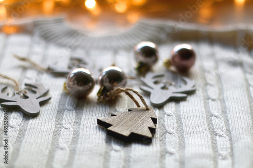 White cable knit sweater and various Christmas decorations on wooden background. Selective focus.