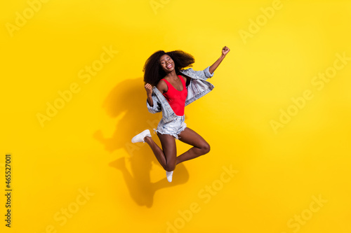 Full length body size photo of girl jumping high gesturing like winner stylish outfit isolated on bright yellow color background