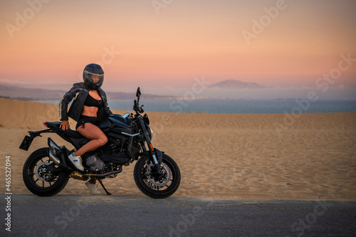 Mujer joven sexy y atl  tica sentada en su moto al atardecer en las dunas de Tarifa  C  diz  Andaluc  a  Espa  a