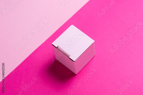 Simple pink cardboard box on color background, top view