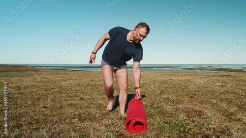 Adult man does Tibetan gynastics Oko of Renaissance on ground of Yamal peninsula in summer. Staying healthy and strong. photo