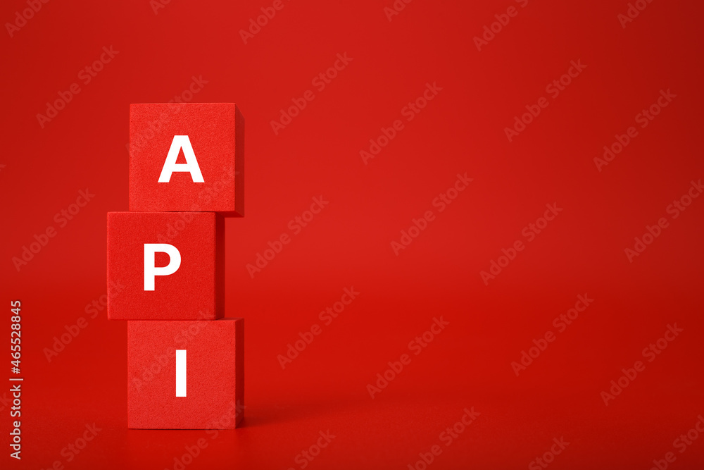 API concept in monochromatic red colors with copy space. API written on stack of red toy cubes