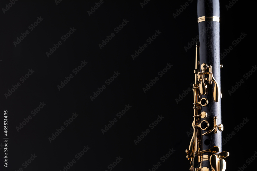 Naklejka premium Part of a clarinet with gold plated keys on a black background. A woodwind instrument common to classical music.
