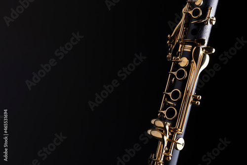 Part of a clarinet with gold plated keys on a black background. A woodwind instrument common to classical music.