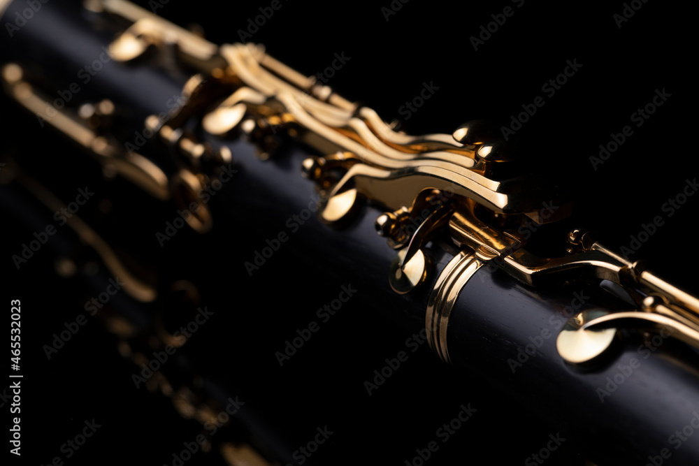 Naklejka premium Part of a clarinet with gold plated keys on a black background. A woodwind instrument common to classical music.