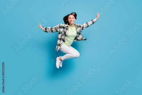 Full body profile side photo of young cheerful girl happy positive smile fly air jump isolated over blue color background