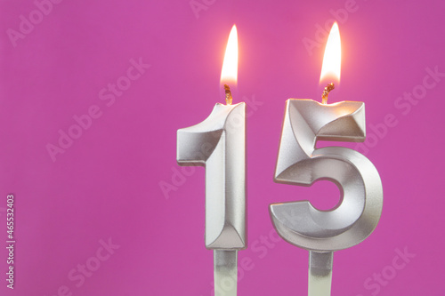 Silver birthday candles on pink background with copy space for text, number 15