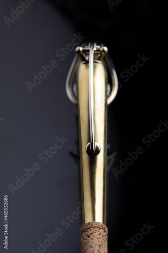 A raw brass neck of a saxophone on a dark background