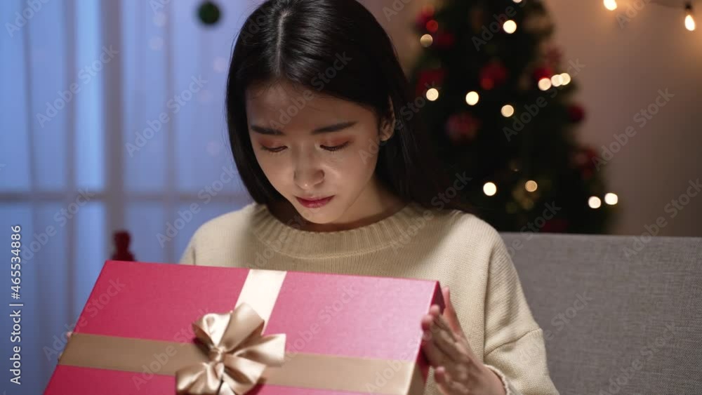 Beautiful asian japanese girl watching in box something bright. surprised woman open mouth big while looking at light inside present. happy female shocked emotion while receiving gift at home Beautiful asian japanese girl watching in box something bright. surprised woman open mouth big while looking at light inside present. happy female shocked emotion while receiving gift at home