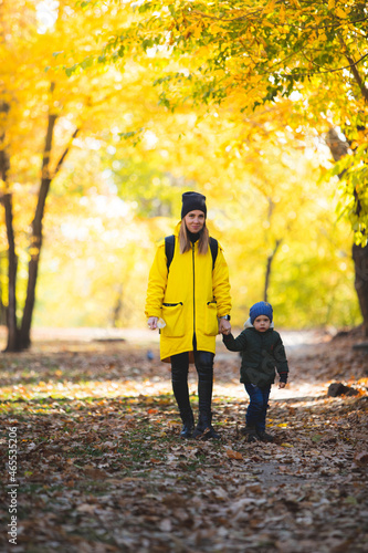 boy in autumn leaves walking with mom