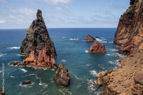 sharp orange big rock formed like a triangle looking out of the ocean near the shore of madeira
