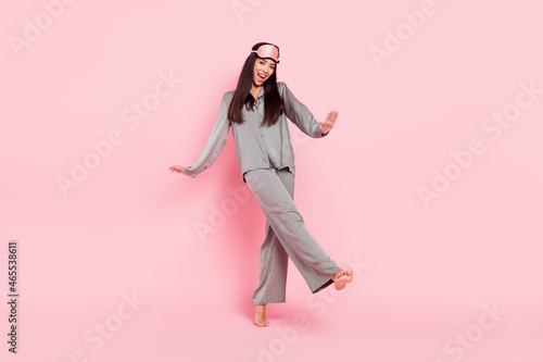 Full length photo of charming shiny lady sleepwear mask dancing walking smiling isolated pink color background